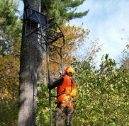 A man climbs to his tree stand wearing a full body harness for safety.