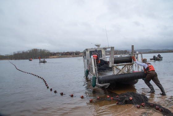 group of men pushing fishing boat into Mississippi River