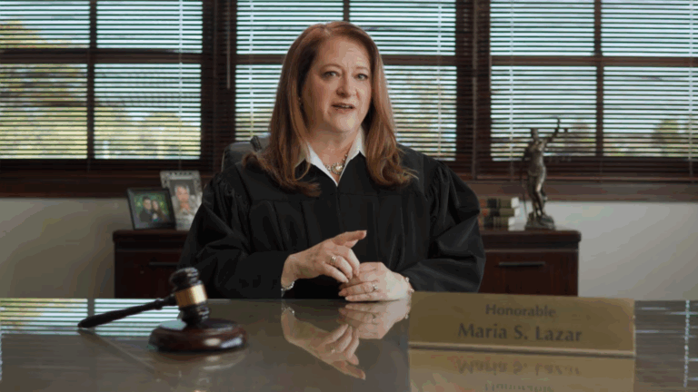Image of Supreme Court candidate Judge Maria Lazar seated before a large desk wearing judicial robes.