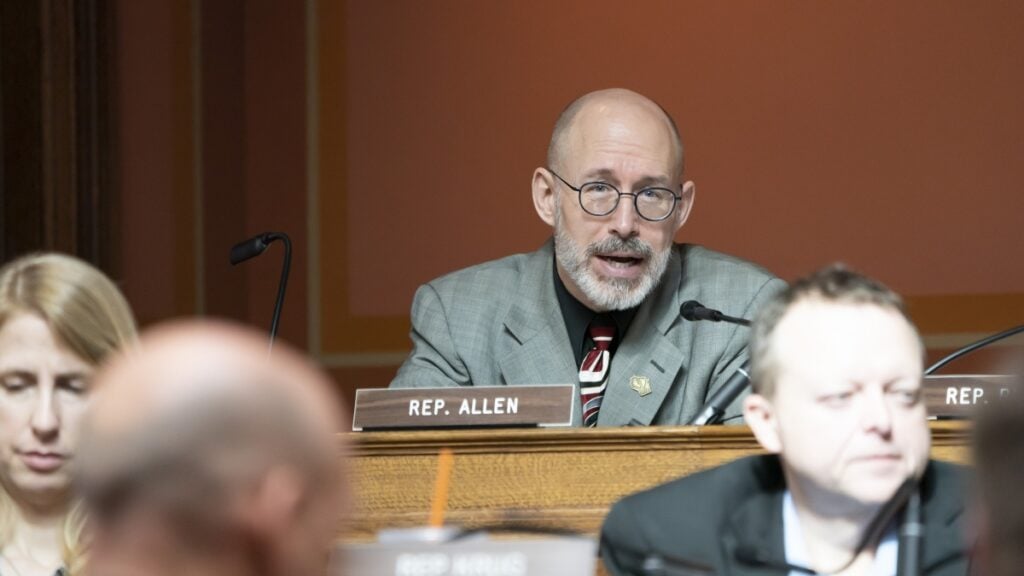 This image shows Rep. Scott Allen seated in a hearing room at the Wisconsin State Capitol.
