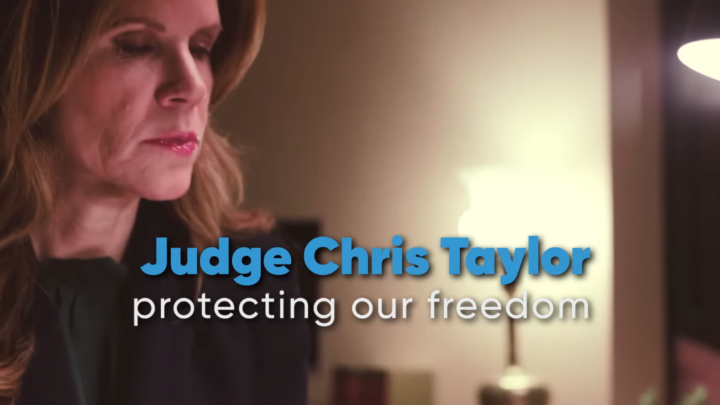 Screenshot from an ad by A Better Wisconsin Together Political Fund supporting Supreme Court candidate Judge Chris Taylor. The image shows a picture of Taylor, with text to the right of her name and "protecting our freedom."