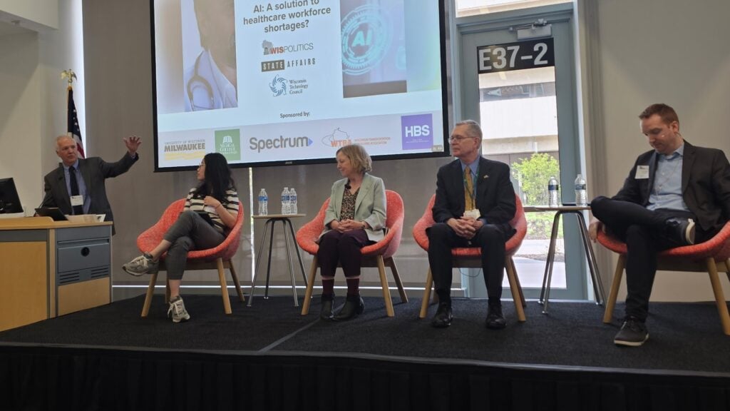 This image show panelists on a stage in a brightly lit room discussing AI in healthcare.