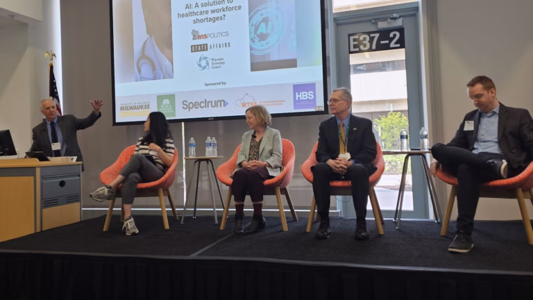 This image show panelists on a stage in a brightly lit room discussing AI in healthcare.