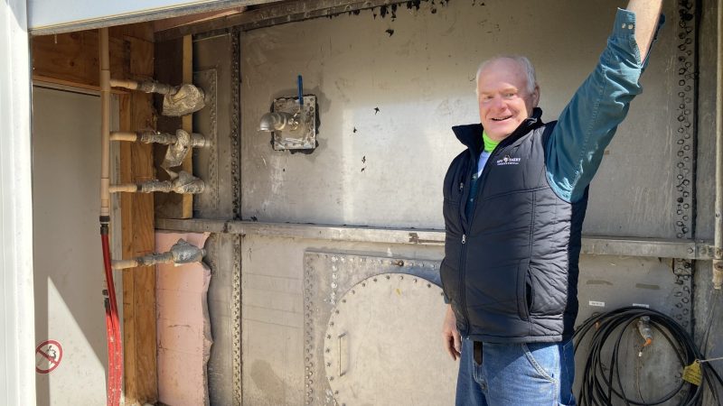 Tom Crave holds open the door to the side of the manure digester tank. The tank is warm to the touch at over 101 degrees, imitating a cow's stomach to further "digest" the manure. Image by Stephanie Hoff, April 2, 2021