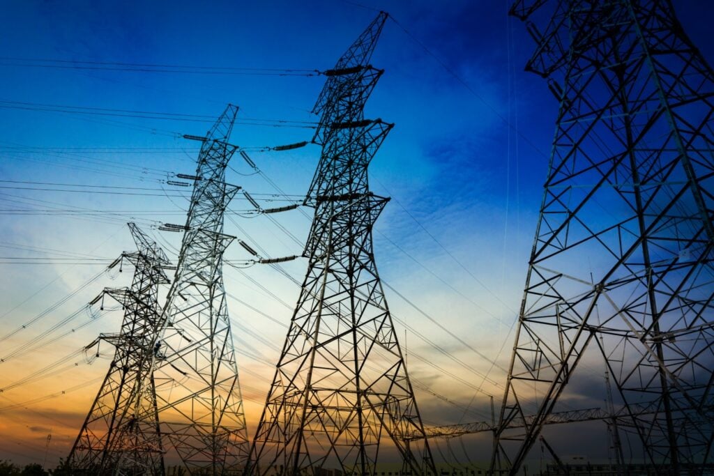 Sun setting behind the silhouette of transmission lines.